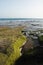 Zahara beach of the tuna with greenish rocks by seaweed with the sea and blue sky in the background