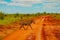 A zebra covered in red sand in Tsavo National Park crosses the road