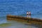 ZELENOGRADSK, KALININGRAD REGION, RUSSIA - JUNE 18, 2019: Two unknown boys on the wooden breakwater on the Baltic Sea coast in