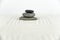 Zen garden. Pyramids of white and gray zen stones on the white sand with abstract wave drawings.