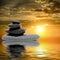 Zen massage stones at sunset reflected in water