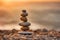 Zen stones stacked forming a pyramid on a rock, against the backdrop of the sunset, symbolizing harmony.