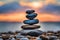 Zen stones stacked forming a pyramid on rocks, against the backdrop of the sunset, symbolizing harmony.