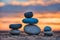 Zen stones stacked forming a pyramid on rocks, against the backdrop of the sunset, symbolizing harmony.