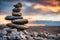 Zen stones stacked forming a pyramid on rocks, against the backdrop of the sunset, symbolizing harmony.