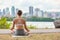 Zen yoga class outside in city park woman wellness meditating in lotus pose outdoor on mat and grass. Girl from behind