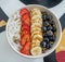 Zenith view of acai bowl super food, shaved coconut, sliced strawberries, bananas and blue berries covered with bee pollen and