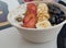 Zenith view of acai bowl super food, shaved coconut, sliced strawberries, bananas and blue berries covered with bee pollen and