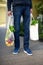 Zero waste concept with copy space. Young man holding cotton shopping bag with vegetables, products. Eco friendly mesh shopper.