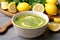 zesty lemon detox soup in a tiled bowl with some lemon slices nearby