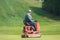 Zhytomyr, Ukraine - May 12, 2016: Fat man gardening grass with a brushcutter at golf field