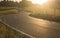 Zigzagging serpentine road between meadows just before sundown metaphorically difficult way. Landscape backlit warm colored