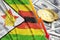 Zimbabwe flag and cryptocurrency falling trend with two bitcoins on dollar bills