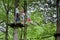 Zloty Potok, Poland - July 23, 2016: Visitors in adventure park clambering with ropes wear protective helmets.