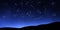 Zodiac signs on clear night sky above mountains