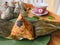 Zongzi is placed on the green plate on the leaf, on the wooden tray,and a cup of tea beside