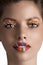 Zoom on a girls face with rainbow lips and candy