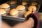 Zoom of hand with kitchen glove put or take bread from inside oven. rear view of hand taking fresh bread