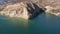 Zoom out the aerial footage of a beautiful white boat cruising emerald clean waters of Castaic lake near Los Angeles on