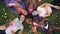 Zoom-out of cheerful friends multiracial group resting on grass after party with colorful faces and clothing moving