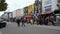 ZOOM OUT from the famous wall decorations above tourist shops on Camden High Street to reveal shoppers on the very busy sidewalk