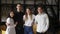 Zoom out portrait of four multiethnic young people standing together in group looking at camera posing at library or in