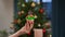 Zoom out from slim female Caucasian hand showing delicious pastry with toy Christmas tree 2022. Unrecognizable