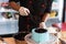 Zoom of pastry chef hand using rubber gloves pouring melted chocolate to blue round cake