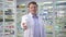 Zoom in portrait of confident smiling male pharmacist stretching multivitamin complex bottle looking at camera