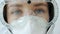 Zoom-in portrait of serious woman doctor wearing safety uniform mask, suit and respirator