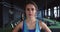 Zoom in portrait, serious young beautiful female athlete looking at camera, tired after intense workout at health club.