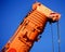 Zoom shot of an orange-coloured truck-mounted crane with telescopic boom pushed together