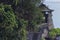 Zoom shot of a temple on top of a cliff with a staircase towards it in Tanah Lot, Bali