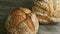 Zoom in at two whole round wheat bread on wooden table