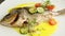 Zoom in at whole roasted fish and vegetables spin around on plate