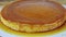 Zoom in at whole round homemade milk soft flan with caramel syrup on white plate