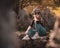 Zoomed full body portrait of an attractive brunette sitting on a well at the Rajcica wells natural landmark. Girl wearing jeans