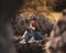 Zoomed full body portrait of an attractive brunette sitting on a well at the Rajcica wells natural landmark. Girl wearing jeans