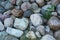 Zoomed pile of large stones or rocks with green plants growing between. Above view of rocky landscape along a remote