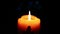 Zooming in on Christmas candle with ornaments burning  in a dark room.  Warm yellow candle gently burning in the dark .