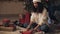 Zooming view of attractive happy mulatto girl in santas hat preparing presents. She cutting paper, wrapping gift sits