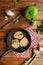 Zucchini fritters on a black small pan, red checkered napkin, silver vintage Cutlery, green zucchini, greens, sauce bowl with