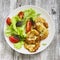 Zucchini pancakes and fresh vegetable salad on white plate