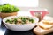 zuppa toscana in white bowl, bread slice resting on edge