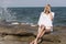 Î’londe woman sitting on sea rocks