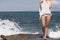 Î’londe woman standing on sea rocks