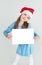 Ð¡ute girl in Santa Claus hat with a white blank paper sheet. Ð¡