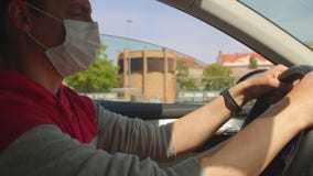 ο οδηγός κρατά το τιμόνι με τα χέρια του. μια μάσκα φοριέται στο πρόσωπό  του. απόθεμα βίντεο - Βίντεο από automatism: 233121421