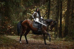 A Beautiful Warrior Girl With A Sword Wearing Chainmail And Armor Riding A Horse In A Mysterious Forest. Stock Images A Beautiful Warrior Girl With A Sword Wearing Chainmail And Armor Riding A Horse In A Mysterious Forest. Stock Images