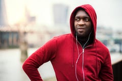 A Close-up Of Black Man Runner With Earphones And Hood On His Head In A City. Copy Space. Royalty Free Stock Images